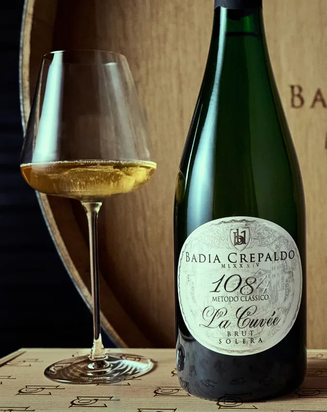 Bottiglia di 1084 La Cuvée Metodo Classico con calice di spumante